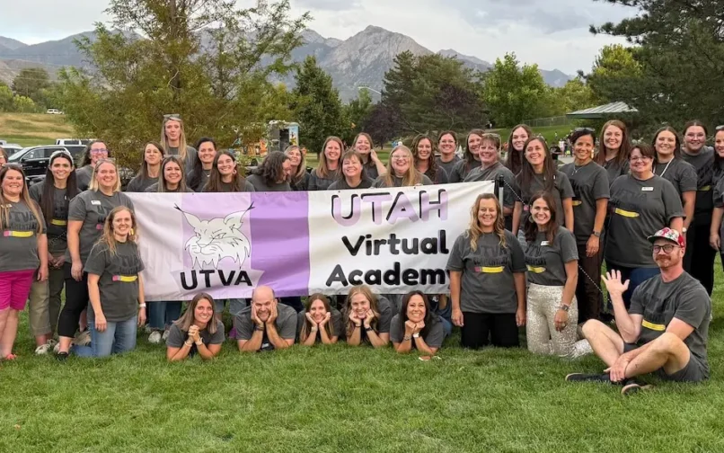 Group of Utah Virtual Academy staff outdoors holding a banner with UTVA logo.